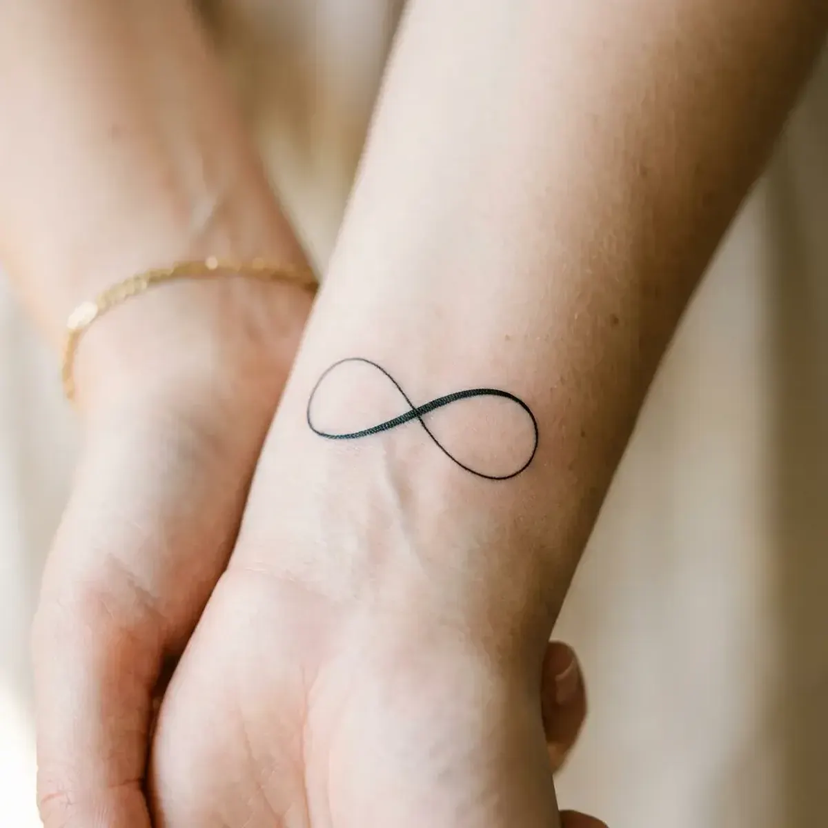 Minimalist fine-line infinity symbol tattoo on inner wrist